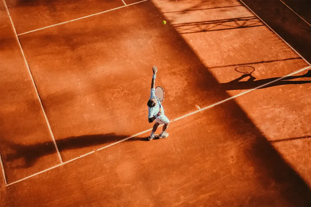 big orange tennis court with a player at the center shooting a ball