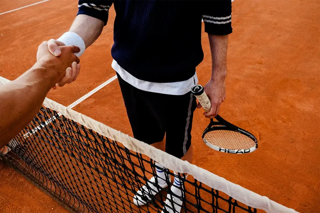 people shaking hands in a tennis court